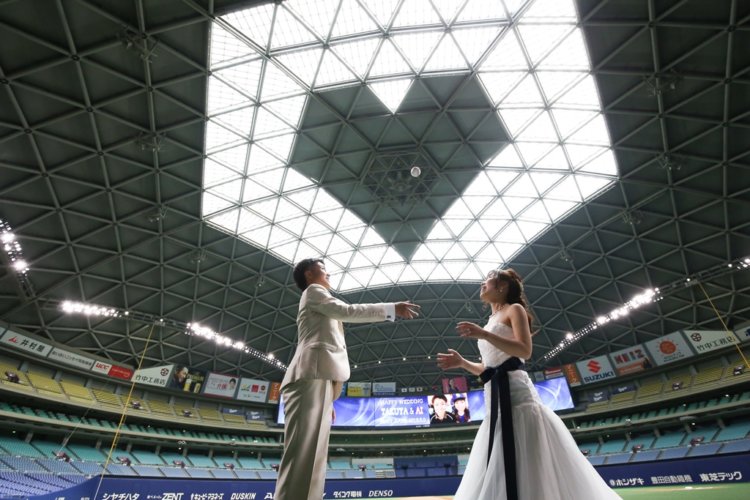 スタジアムの天井に映し出された大きなハートを見上げる新郎新婦