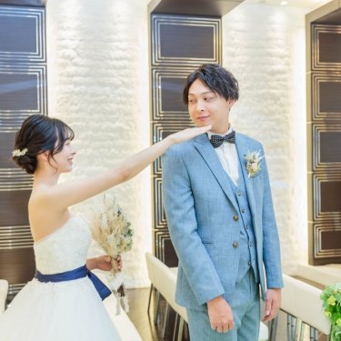 チャペルで振り向く前の新郎の頬に手を添える花嫁。ファーストミートを残す水色のスーツのチャペルフォト