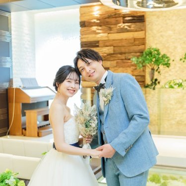 木の壁のチャペルで頬を寄せる水色のスーツの新郎とドライフラワーのブーケの花嫁のチャペルフォト