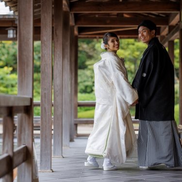 大仙公園の回廊で手をつないで振り返る白無垢の花嫁と紋付袴の新郎。日本庭園の和装前撮り