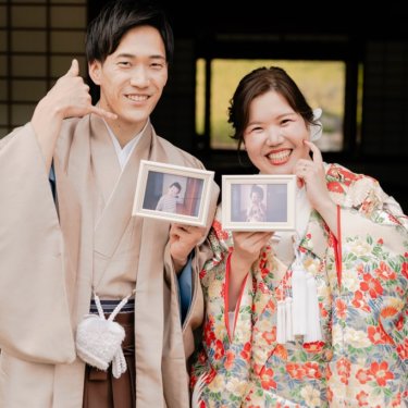 大仙公園の茶室で幼い頃の写真を持って笑う羽織袴の新郎と色打掛の花嫁。思い出の小物を使った和装前撮り