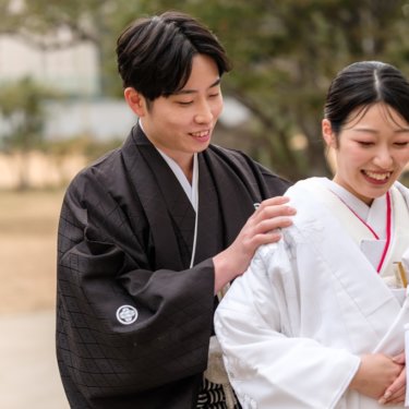 白無垢の花嫁の肩に手を添え、照れ笑いする紋付の新郎と、はにかむ花嫁のアップ。慶沢園の和装前撮り