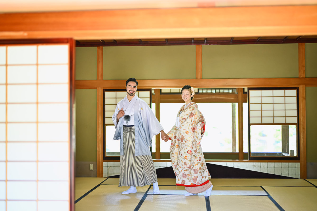 畳と障子のある和室でくつろぐ和装姿の新郎新婦の写真