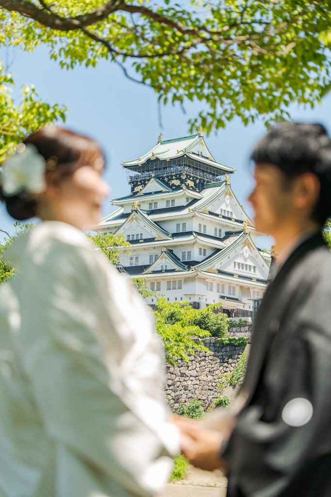 大阪城天守閣を背景に和装で寄り添う新郎新婦