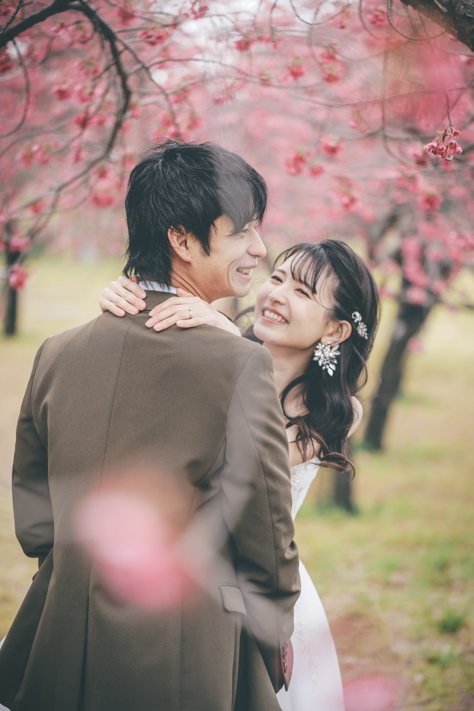 満開の桜並木の下で微笑む新郎新婦