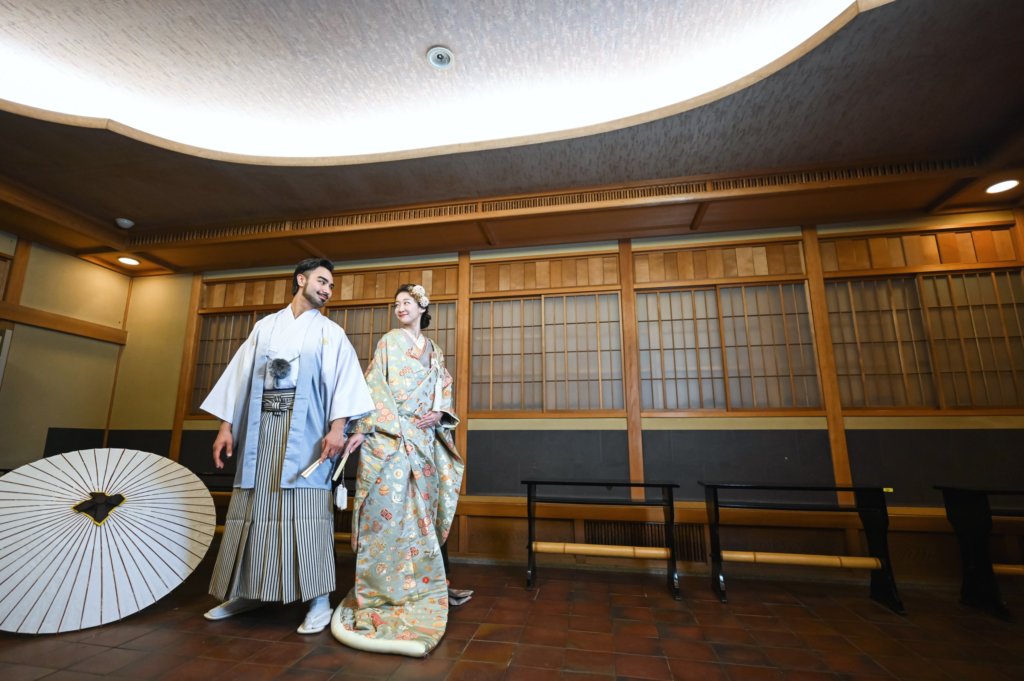 和傘を添えた畳の広間に立つ新郎新婦