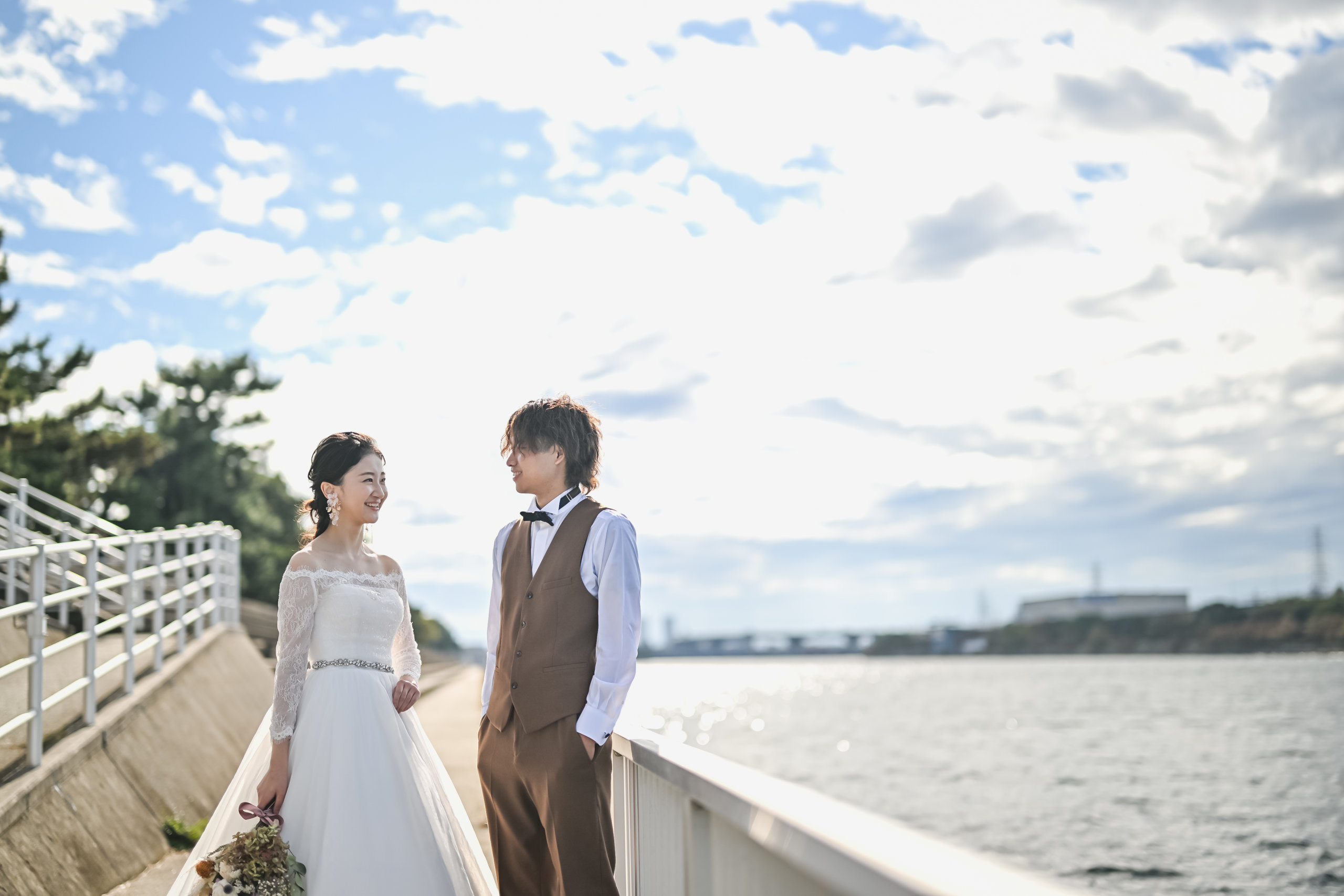 満開のピンクのばらに顔を寄せる花嫁
