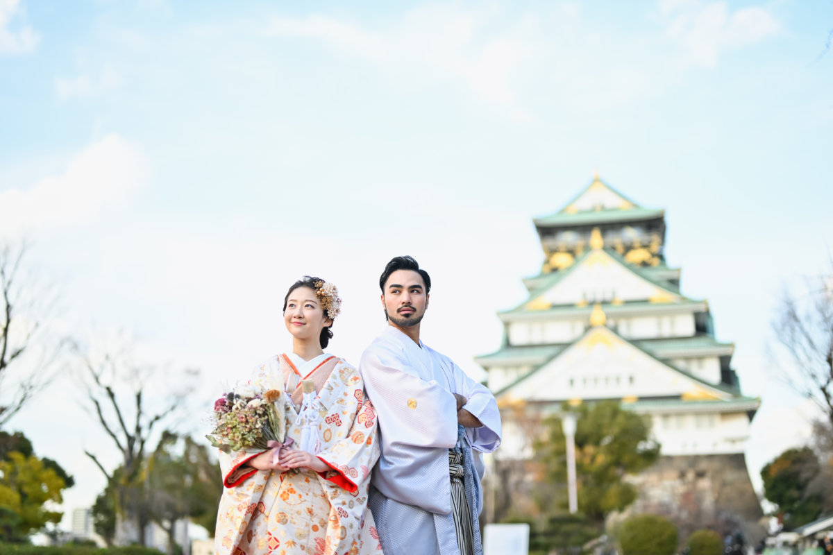 大阪城天守閣を背景に和装で寄り添う新郎新婦
