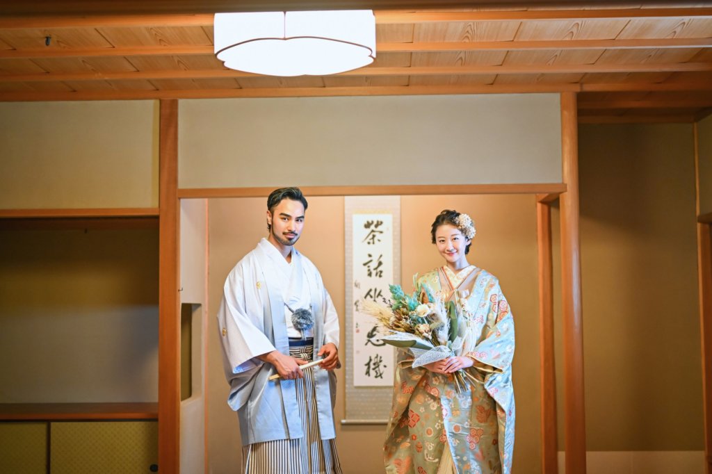 茶室内の掛け軸のある広間に立つ新郎新婦