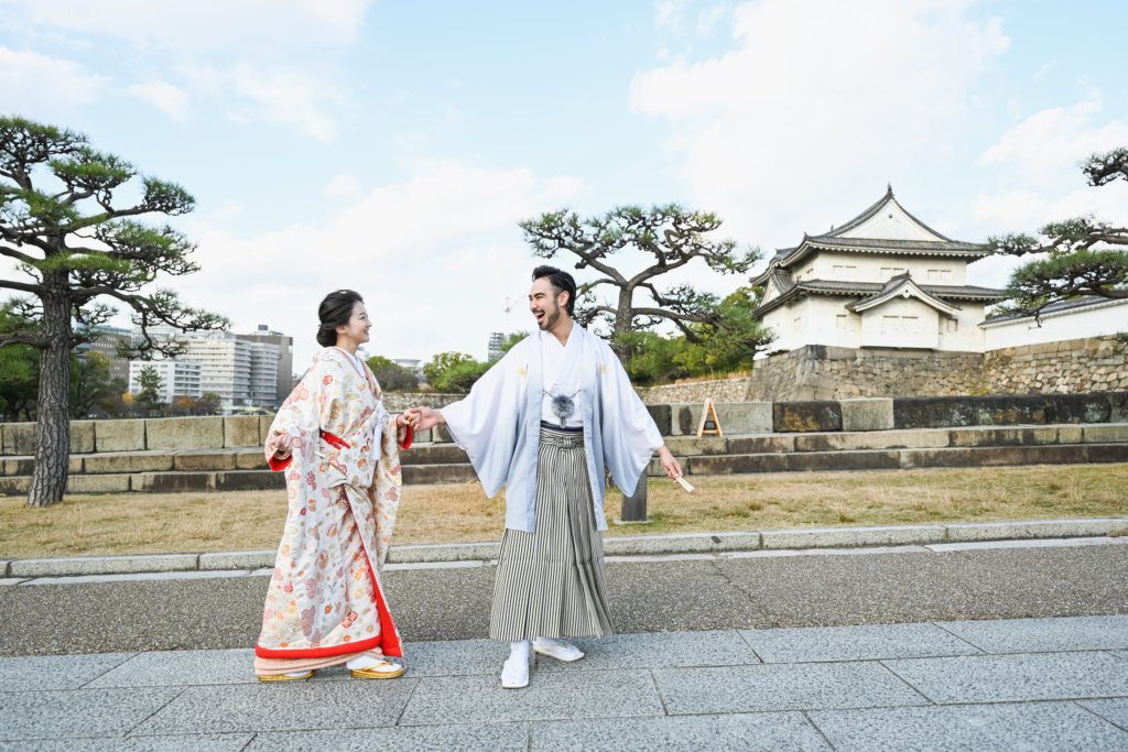 重厚な石垣を背景に和装で寄り添う新郎新婦