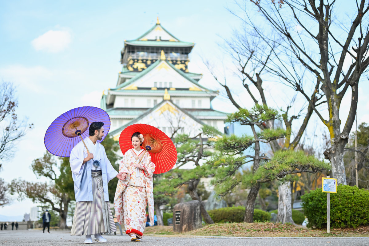 朝の柔らかな光の中、大阪城公園を歩く和装姿のふたり