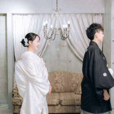 シャンデリアのあるセットで、背を向けて待つ紋付の新郎と近づく白無垢の花嫁。ファーストミートの和装前撮り
