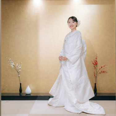 金色の壁の床の間の前に立ち、長い裾を広げてほほえむ白無垢の花嫁の全身ソロカット。心斎橋のスタジオ和装前撮り