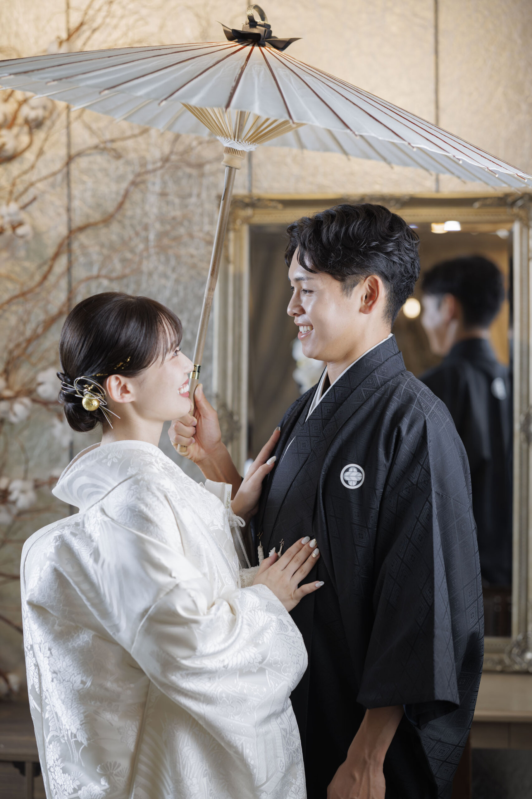 白い和傘の下で見つめ合う和装の新郎新婦