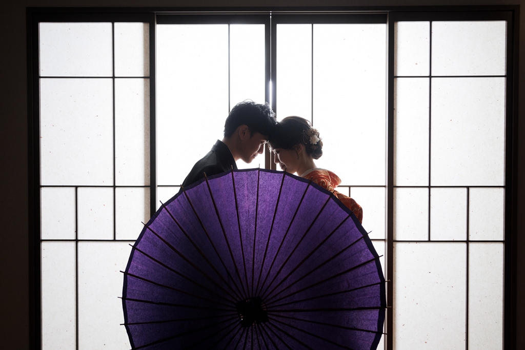 紫の和傘を用いた逆光シルエットの新郎新婦
