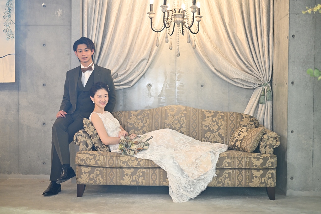シャンデリアとアンティークソファのセットでくつろぐ新郎新婦