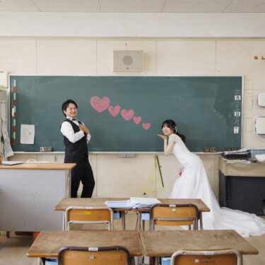 教室全体をとらえた一枚。黒板のハートを挟んでポーズをとる新郎新婦の学校ロケーションフォト