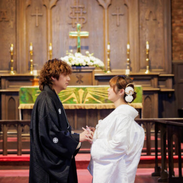 木彫りの祭壇の前で両手を握り合い見つめ合う黒紋付袴の新郎と白無垢の花嫁。川口基督教会で撮るクラシカルな和装前撮り