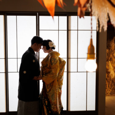 障子窓の前でおでこを合わせる黒紋付袴の新郎と色打掛の花嫁。逆光を生かした大人っぽい和装スタジオフォト