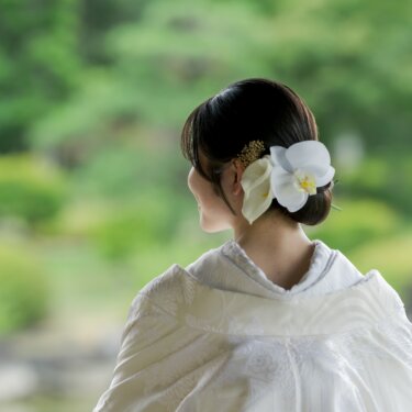 胡蝶蘭とゴールドの髪飾りを付けたシニヨンを後ろから写した、白無垢の花嫁のヘアアレンジのカット。和装前撮りの一枚