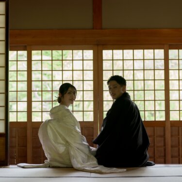障子に囲まれた和室の畳に座り、肩越しに振り返る白無垢の花嫁と紋付の新郎。逆光が美しい和装前撮り