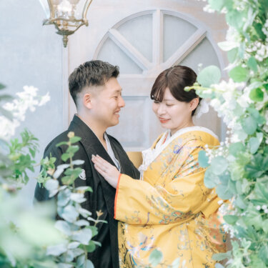 アンティークのランプとグリーンに囲まれたセットで、新郎の胸に手を添える色打掛の花嫁。スタジオで撮る和装前撮り