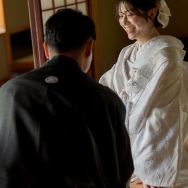 和室の畳に座り、新郎と向かい合って笑う白無垢の花嫁。障子越しのやわらかな光で撮る和装フォトウェディング