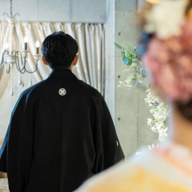 心斎橋店のスタジオで、花嫁の髪飾り越しに黒紋付の新郎の後ろ姿をとらえた、和装前撮りならではの奥行きある構図