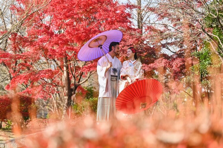 紅葉と和傘を持つ和装姿のふたり